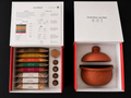 The First Fire boxes open — the ingredient box with five bases, three proteins, four tadka oils and Bloomasala, beside the pot box holding the handmade Mitipot
